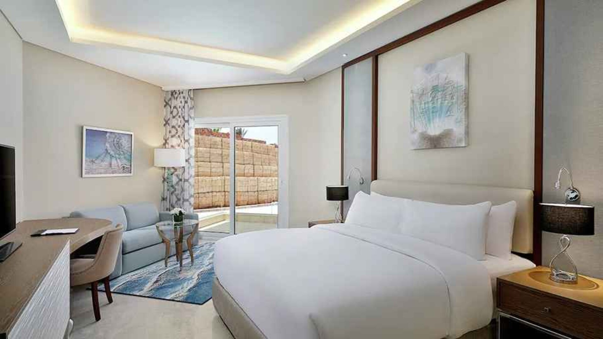 comfortable delux king room with TV, desk, chair, and couch at Hilton Hurghada Plaza.