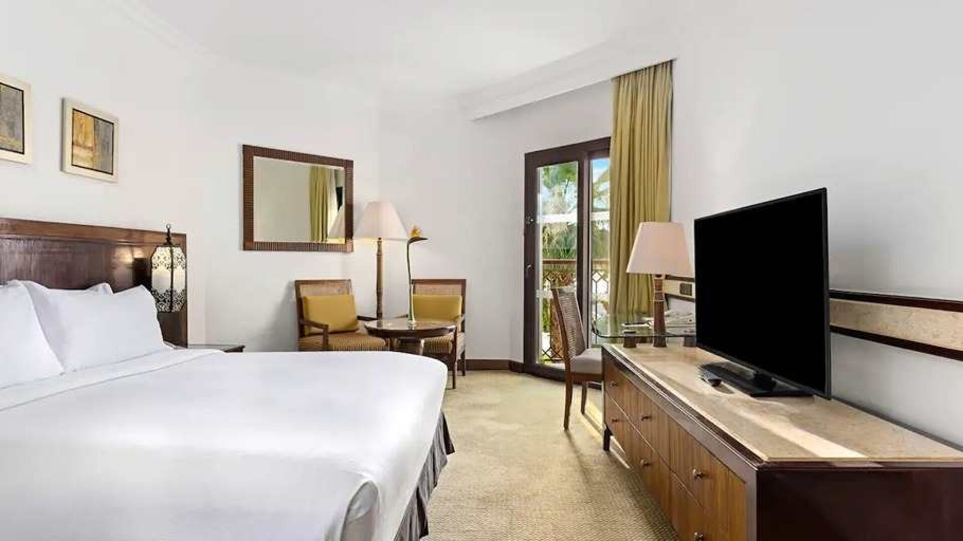 spacious king suite with TV, desk, chair, and dining area at Hilton Luxor Resort & Spa.