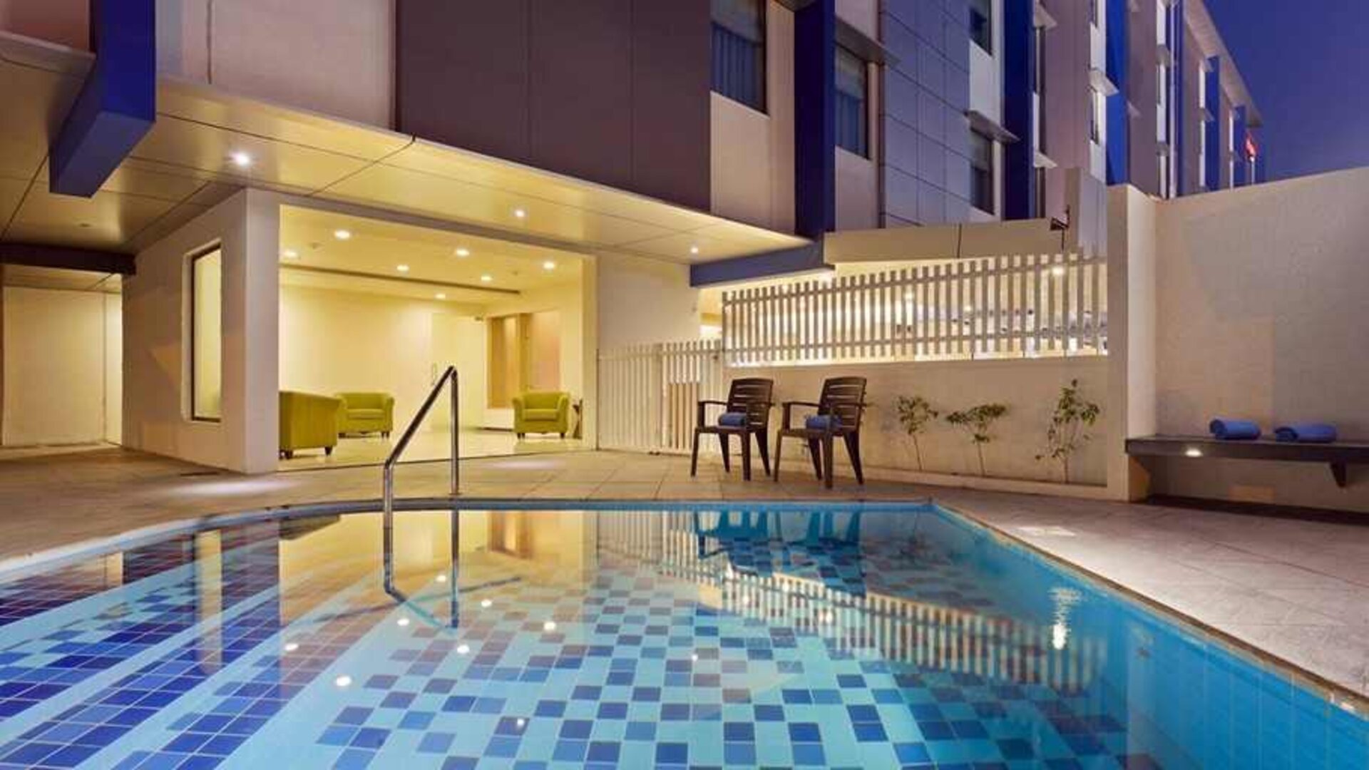lovely outdoor pool with seating area at Hampton by Hilton Vadodara-Alkapuri.