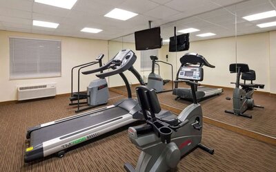 Fitness center equipped with cardio machines and mirrored walls, providing guests with a convenient space to maintain their workout routine during their stay.