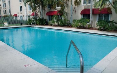 Outdoor pool area surrounded by tropical landscaping, creating a refreshing setting for relaxation and leisure at La Quinta Inn & Suites By Wyndham Sawgrass Mills.