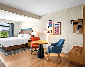 Spacious king room with chair and table and TV. 