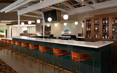Stylish hotel bar offering comfortable seating, premium beverages, and a contemporary social setting at Embassy Suites By Hilton Charleston Airport Convention Center.