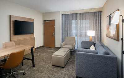 Suite living area featuring a sofa, workspace, flat-screen television, and comfortable seating for extended stays at Embassy Suites By Hilton Charleston Airport Convention Center.