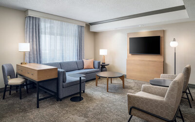 Suite living room with comfortable seating, workspace, and entertainment area designed for relaxation and productivity at Embassy Suites By Hilton Charleston Airport Convention Center.