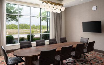 Executive boardroom with large conference table, ergonomic seating, and natural light for productive meetings at Embassy Suites By Hilton Charleston Airport Convention Center.