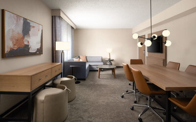 Hospitality suite with conference-style dining table, lounge seating, and flexible space suitable for meetings, collaboration, or relaxation at Embassy Suites By Hilton Charleston Airport Convention Center.