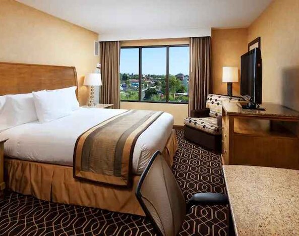 Bright king bedroom with window and working station at the DoubleTree Suites by Hilton Anaheim Resort-Convention Center.