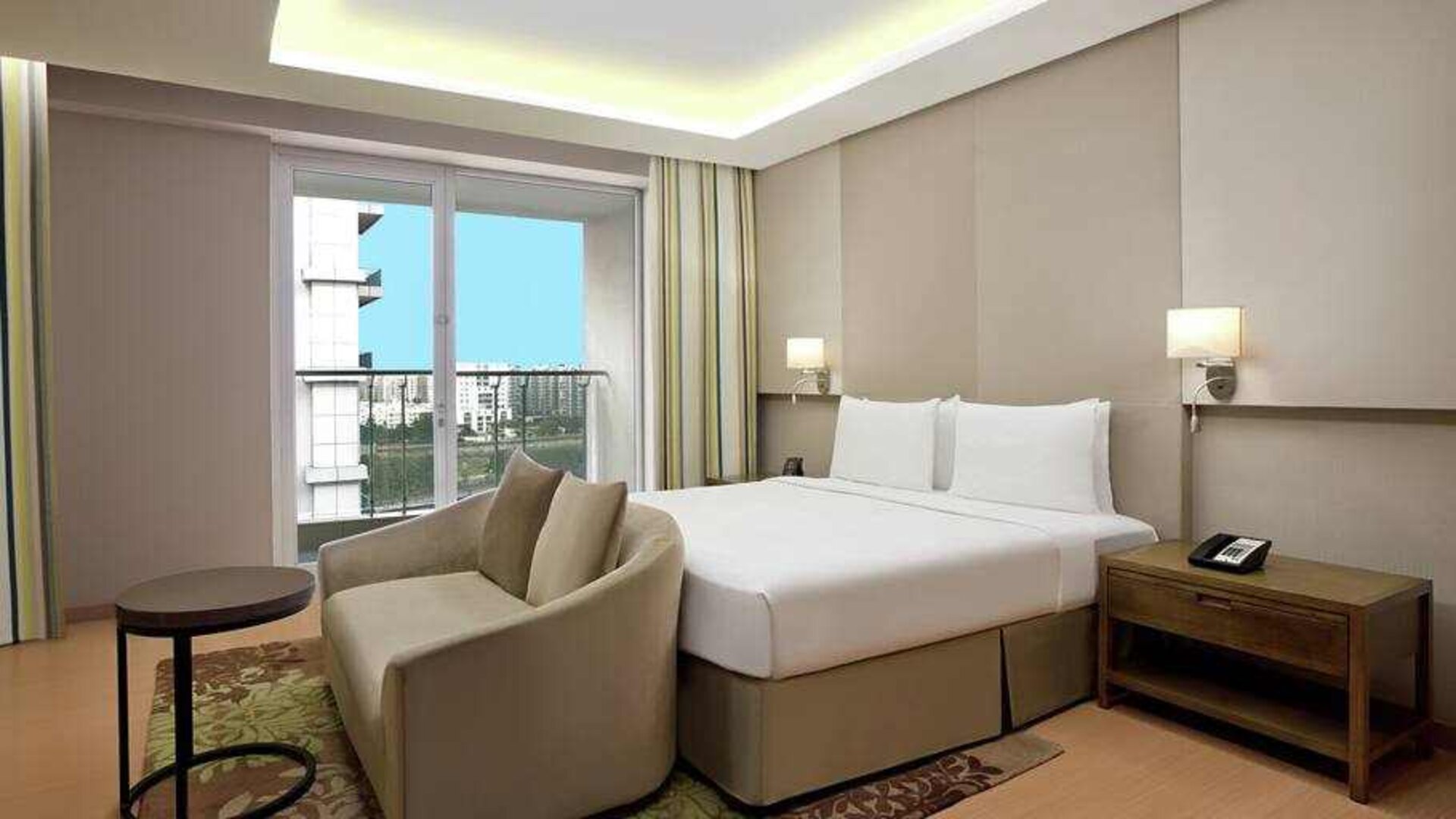 Bright king bedroom with sofa at the DoubleTree Suites by Hilton Bangalore.
