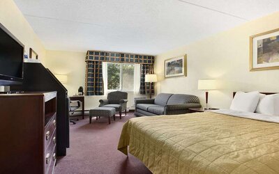King bedroom with TV screen and workstation at Travelodge Ottawa East.