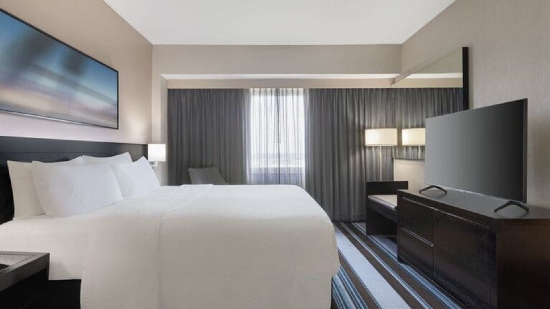 Comfortable king room with TV and couch at Courtyard By Marriott New York JFK Airport.