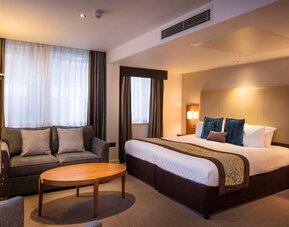 Wide view of the Thistle Trafalgar Square executive king room, featuring large bed, sofa, and TV.