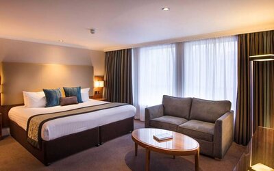 Wide view of the junior suite double room, with small sofa, coffee table, and spacious bed.
