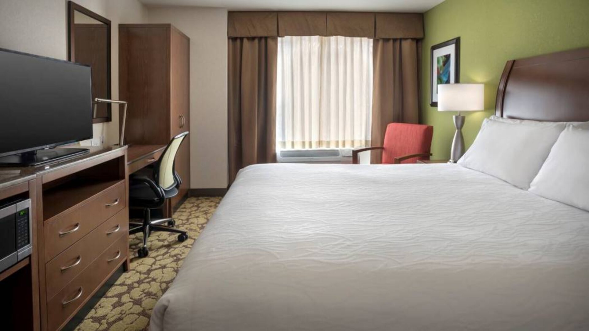 Guest room in the Hilton Garden Inn Chicago Downtown Riverwalk, including large bed, window, and desk and chair for working.