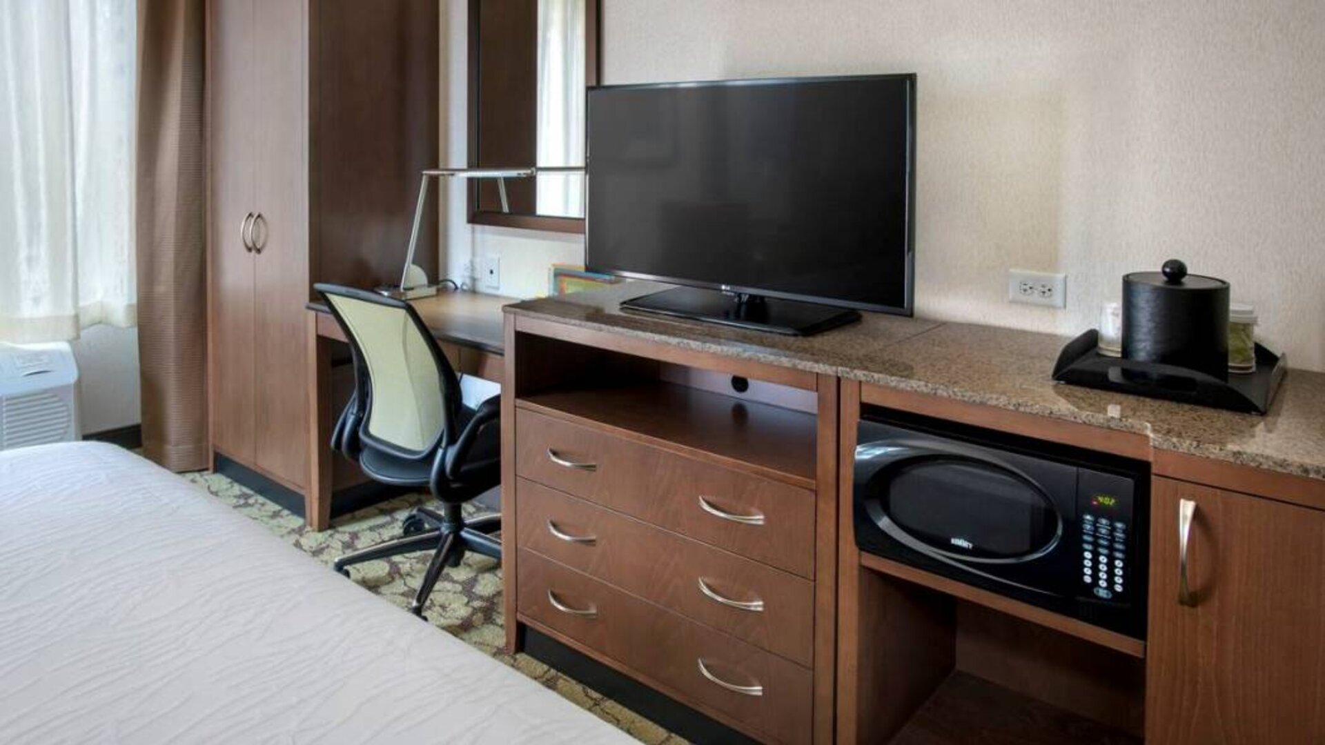 Closer view of an in-room workspace, with chair and desk for business, and both a lamp and window nearby.