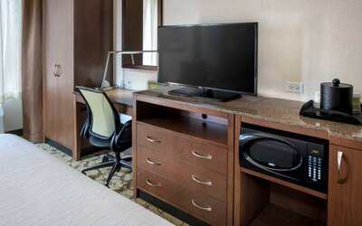 Closer view of an in-room workspace, with chair and desk for business, and both a lamp and window nearby.