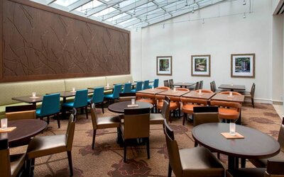 The hotel restaurant offers on-site dining, with varying table sizes and a bright and airy environment.