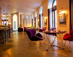 The hotel restaurant has a bar and small tables for diners to enjoy a refined breakfast experience.