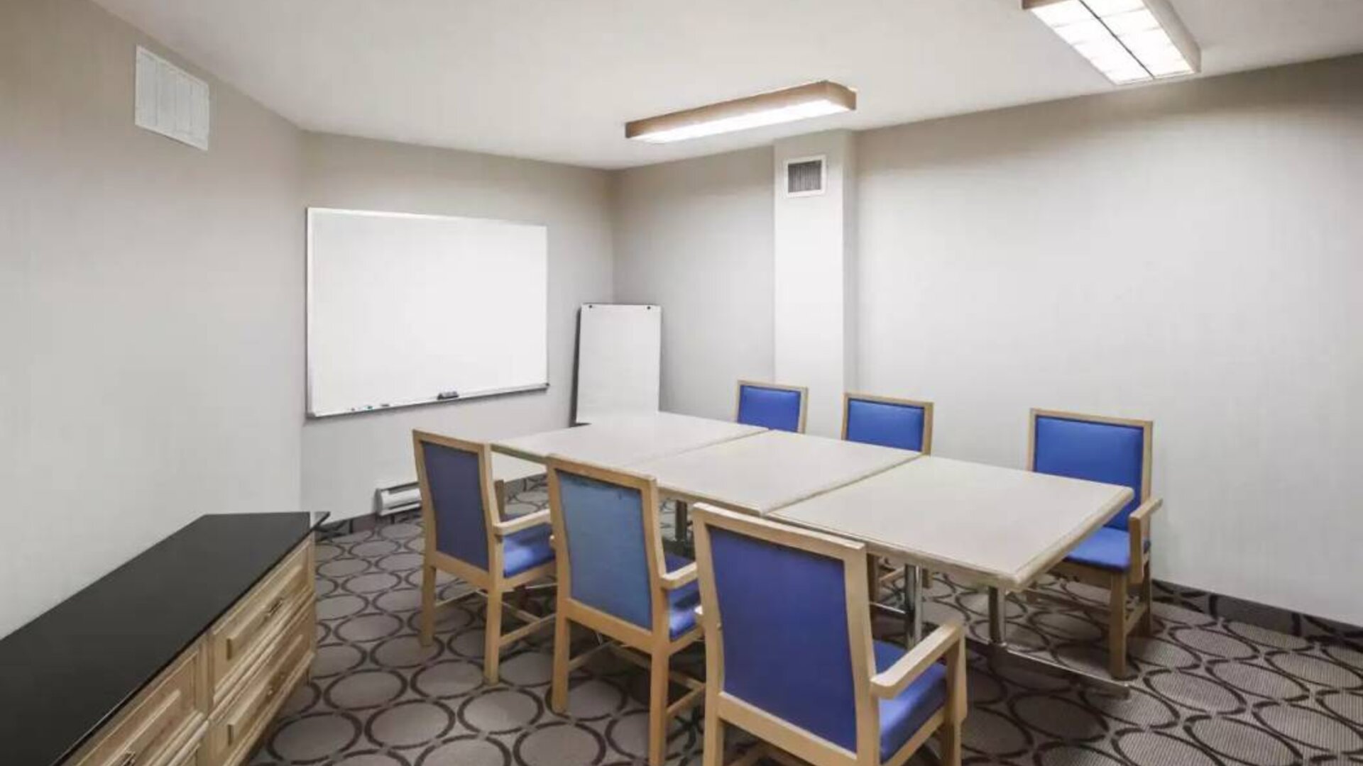 Hotel meeting room with space for half a dozen attendees around a table, and a whiteboard nearby.