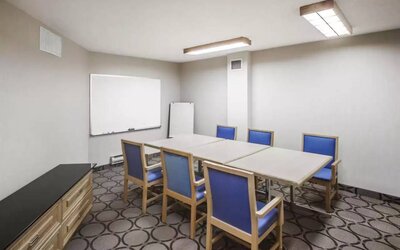 Hotel meeting room with space for half a dozen attendees around a table, and a whiteboard nearby.