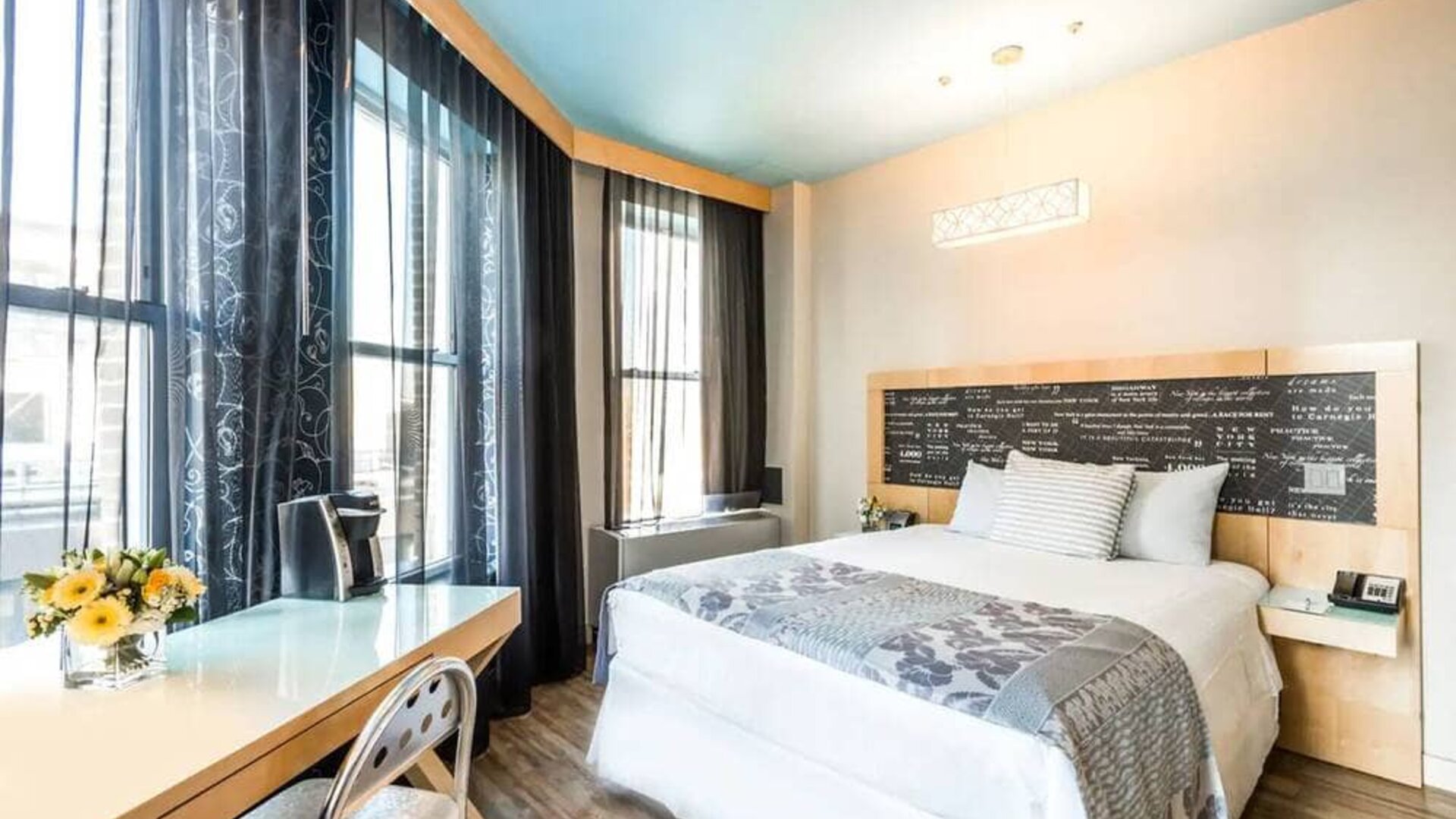 Room at the TRYP By Wyndham Times Square South containing desk, double bed, and large windows.