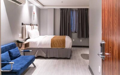 Double bedroom in the Madison LES Hotel, with window, telephone, and seating.