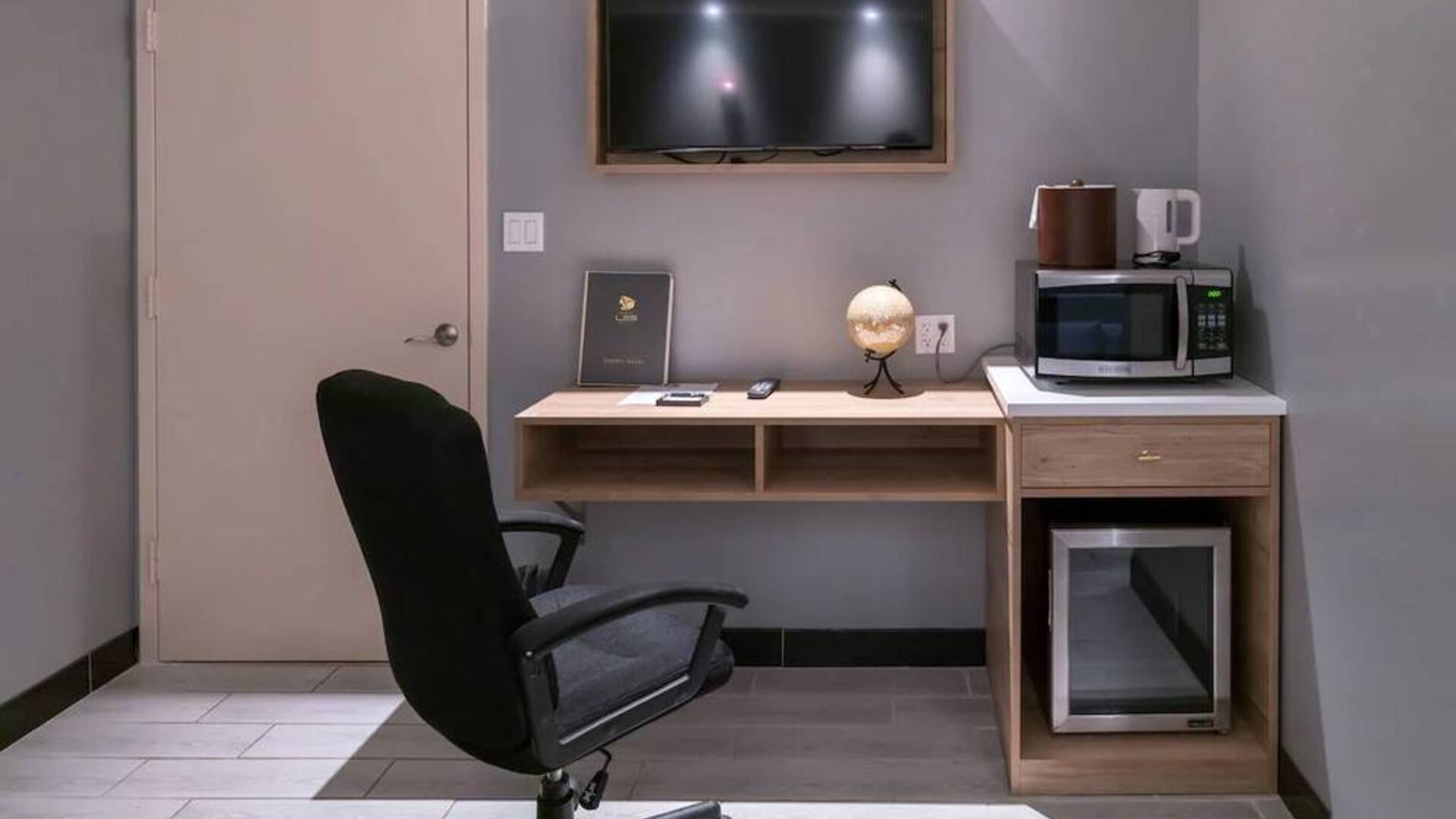 Workspace in a room at the Madison LES Hotel, including desk, chair, and microwave.