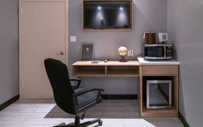 Workspace in a room at the Madison LES Hotel, including desk, chair, and microwave.
