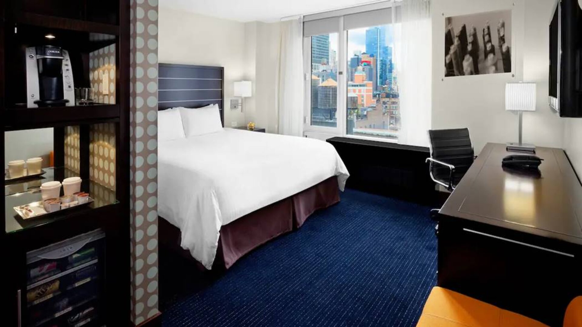 Guest room of the Hilton Fashion District, complete with king-sized bed and workspace desk and chair.