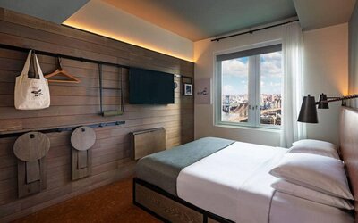 Double bed guest room in the Moxy NYC Downtown, with large TV and window.