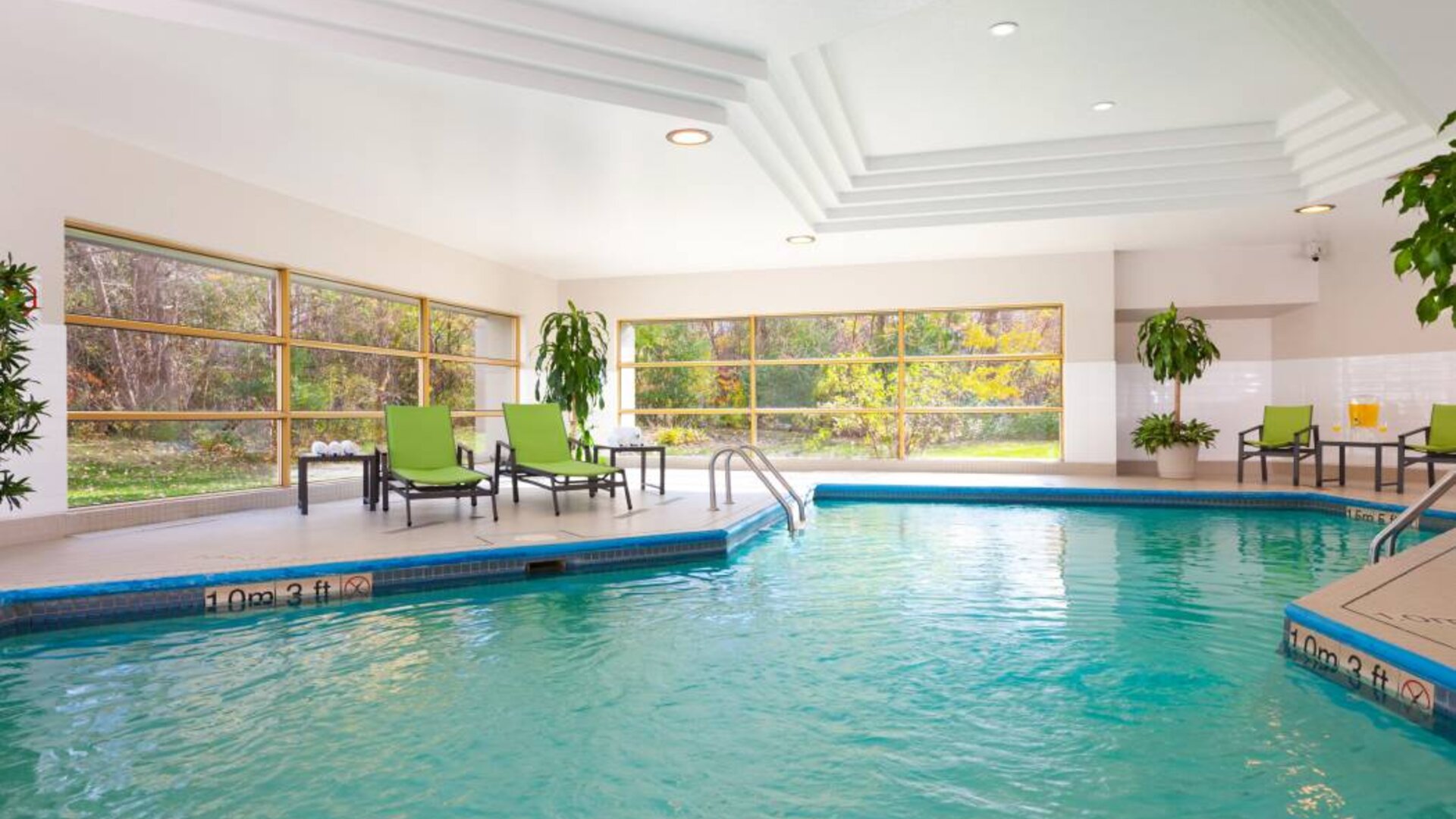 The hotel’s indoor swimming pool is brightly lit and has chairs and loungers by the side.