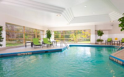 The hotel’s indoor swimming pool is brightly lit and has chairs and loungers by the side.