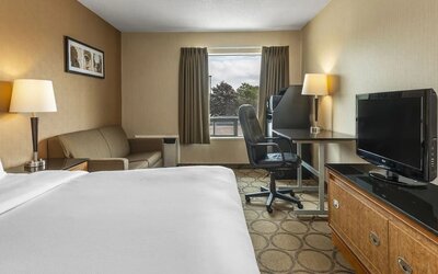 King bedroom with natural light , work space, and TV at Comfort Inn Airport East Ancienne-Lorette.