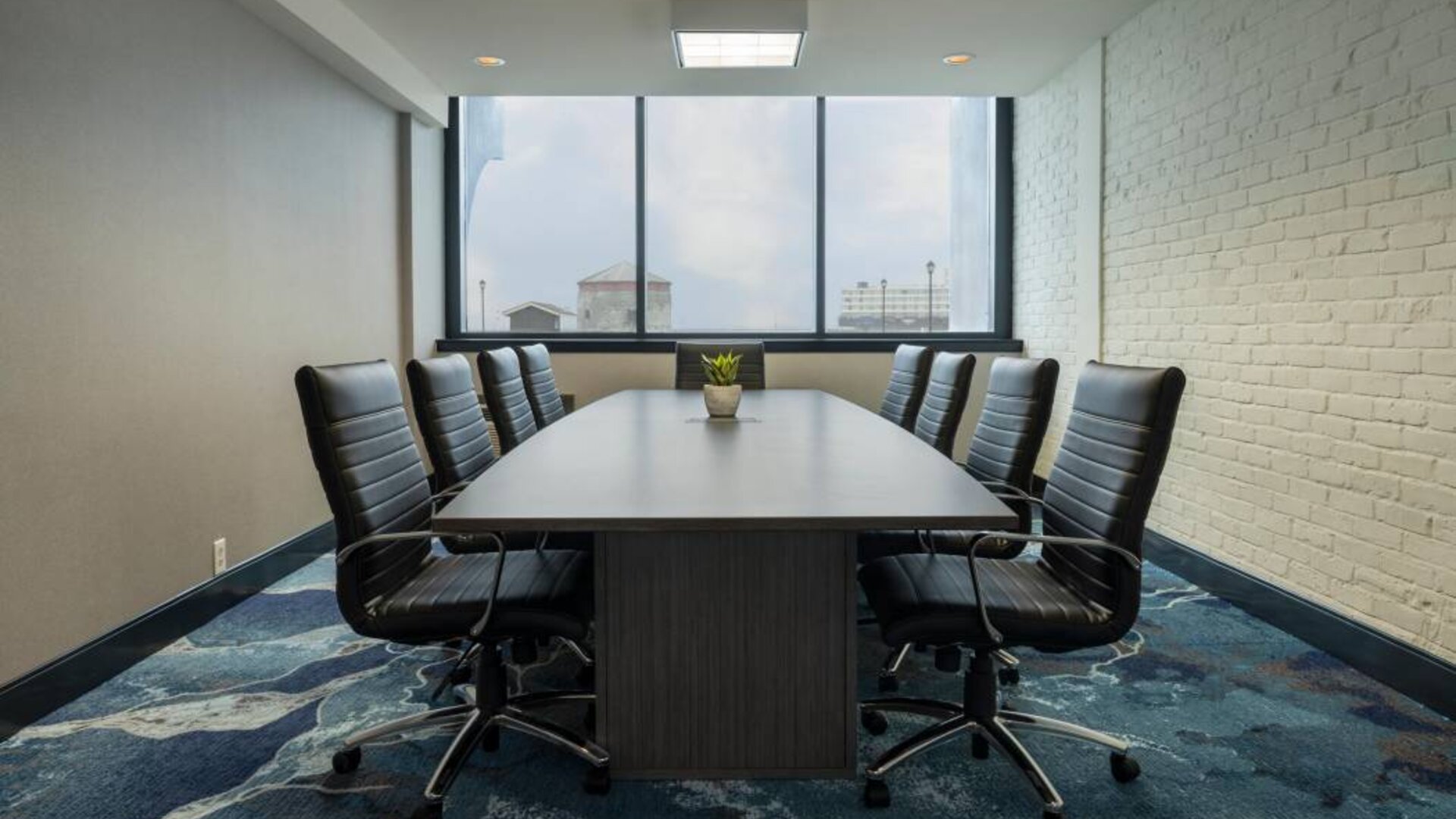 Hotel meeting room with a long wooden table and surrounding leather chairs.
