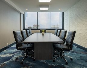 Hotel meeting room with a long wooden table and surrounding leather chairs.