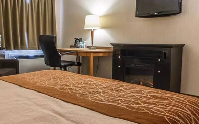 Guest room workspace in Comfort Inn Brandon, with a cozy fireplace beside the desk and chair.