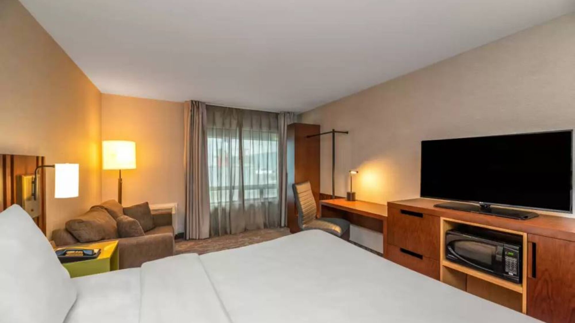 Double bed guest room in Comfort Inn Winnipeg Airport, with sofa and large window.