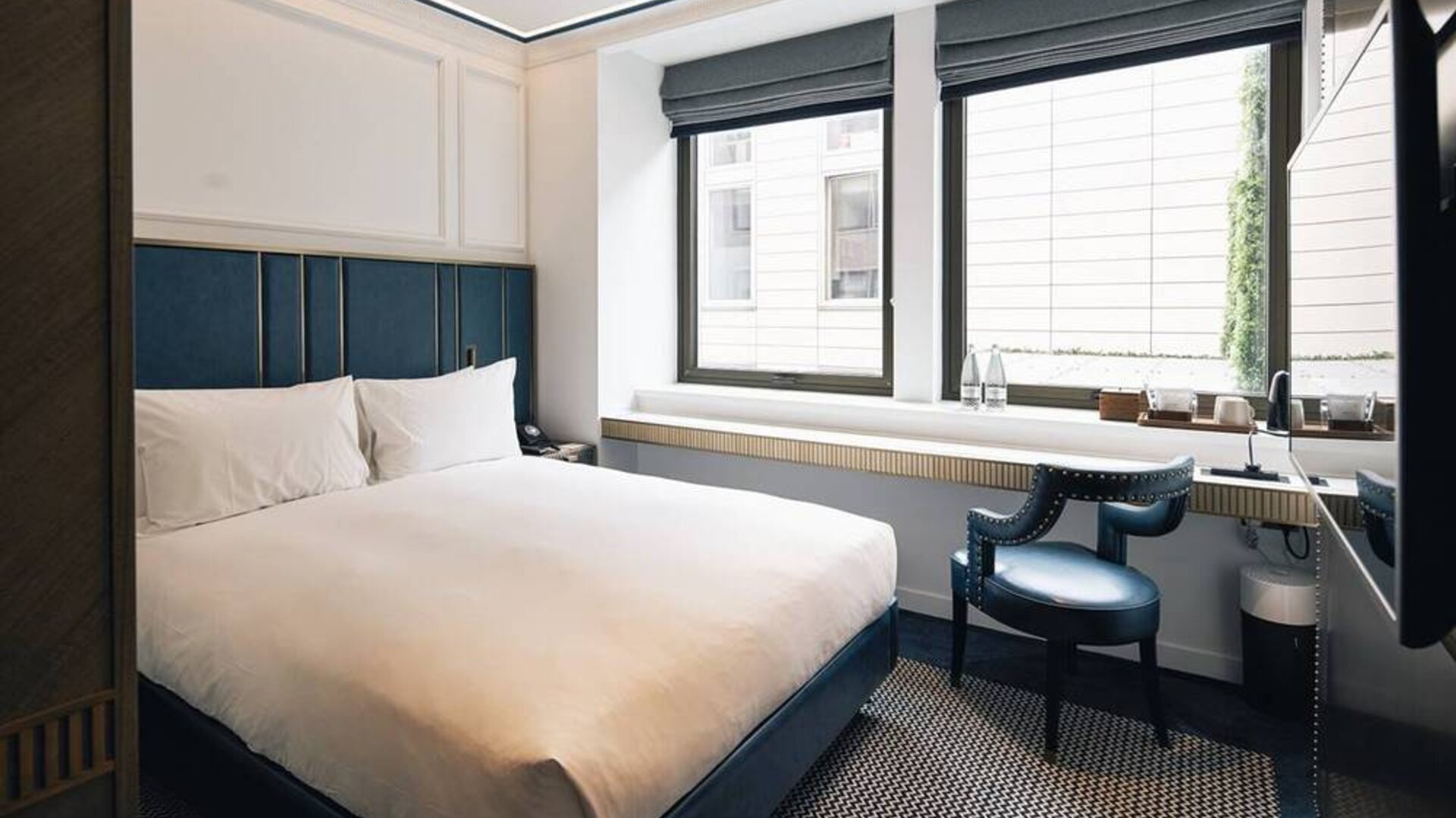 Double bedroom in the Page8 hotel, with nearby chair and plenty of natural light from the windows.