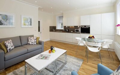 Wider view of the lounge and kitchen area, including sofa, table, and chairs.