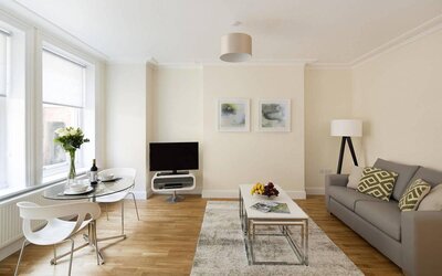 Lounge with sofa, coffee table and chairs, window, and widescreen television.