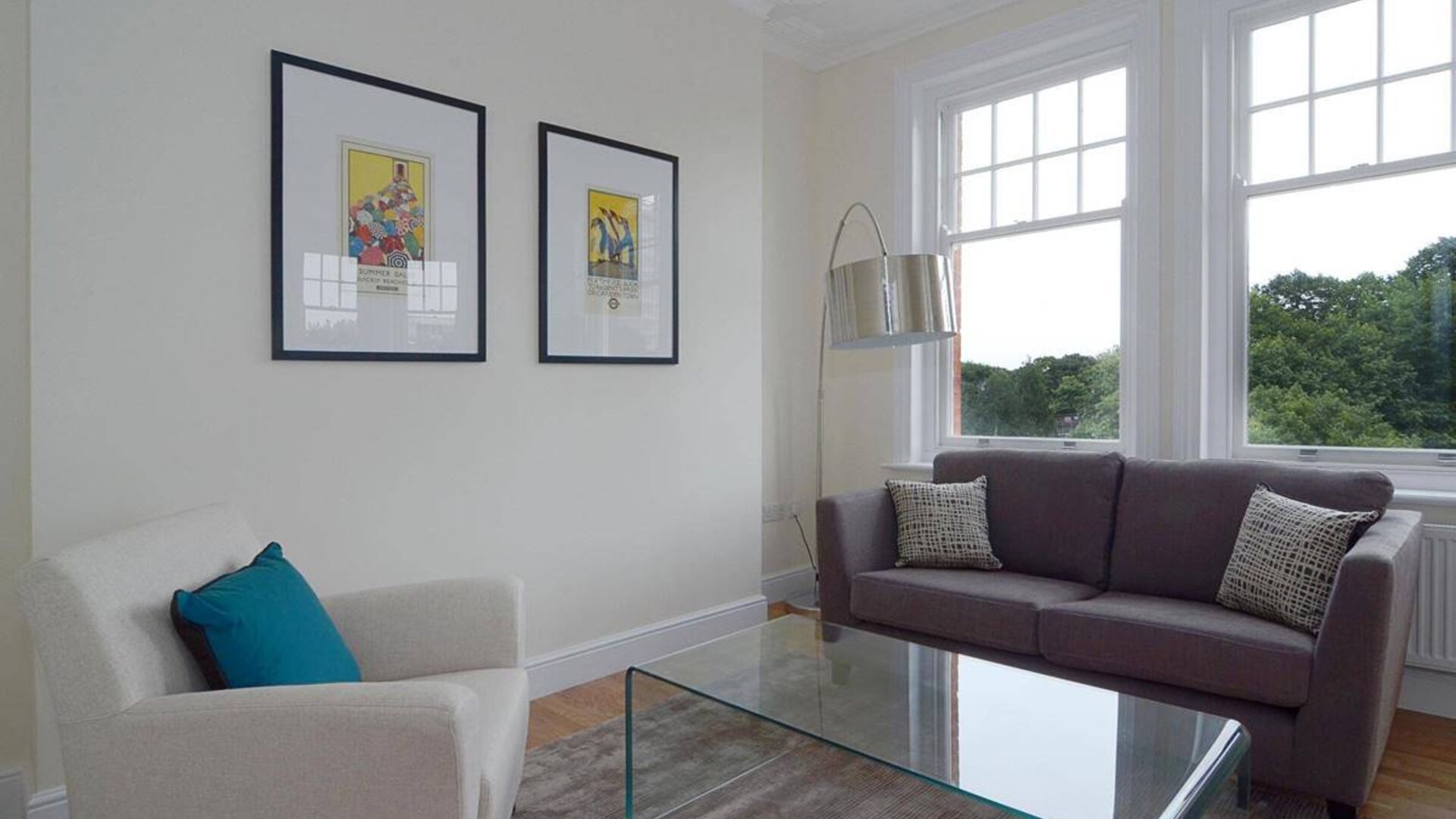 Living room with armchair, sofa, windows, and glass table.