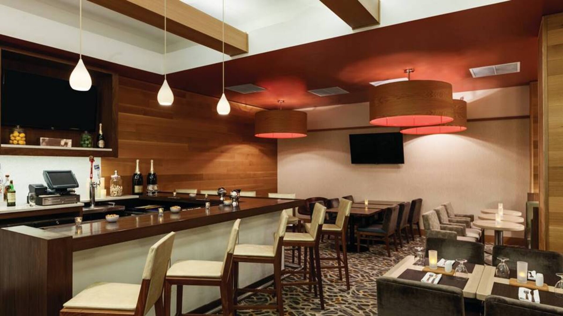The Hilton Garden Inn Midtown East’s restaurant and bar, with tall bar stools, and tables for dining.