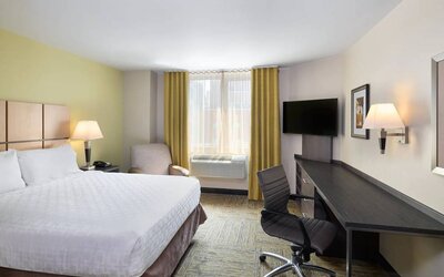 Double bed guest room in the Candlewood Suites Times Square, with workspace nearby and large window.