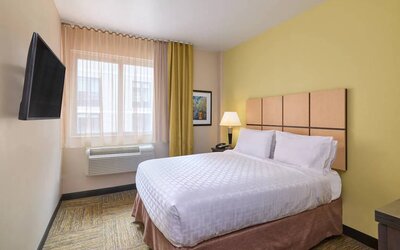A guest room in the Candlewood Suites Times Square, with double bed, large TV, and window.