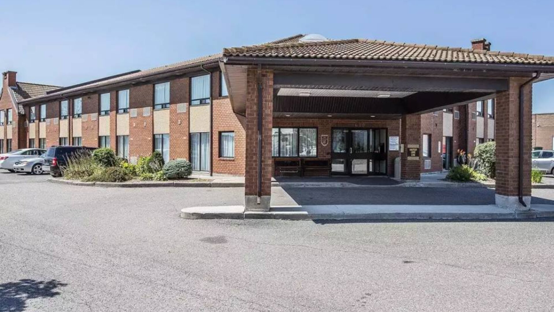 The entrance to Comfort Inn Gatineau is under cover, with nearby greenery and ample parking.