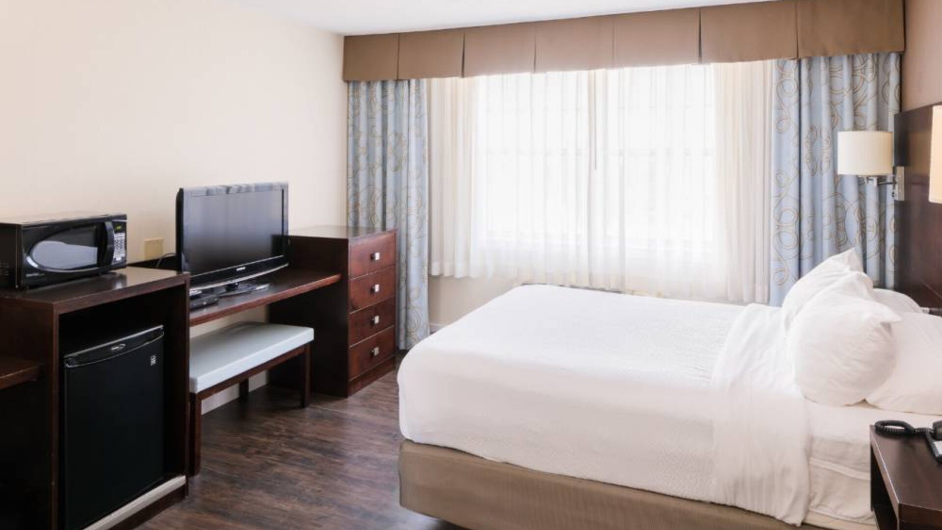 Guest room in Rodd Royalty, with bed, large TV, and big windows.