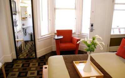 Guest room of The Mosser Hotel, with bed, chair, windows, and ensuite bathroom.