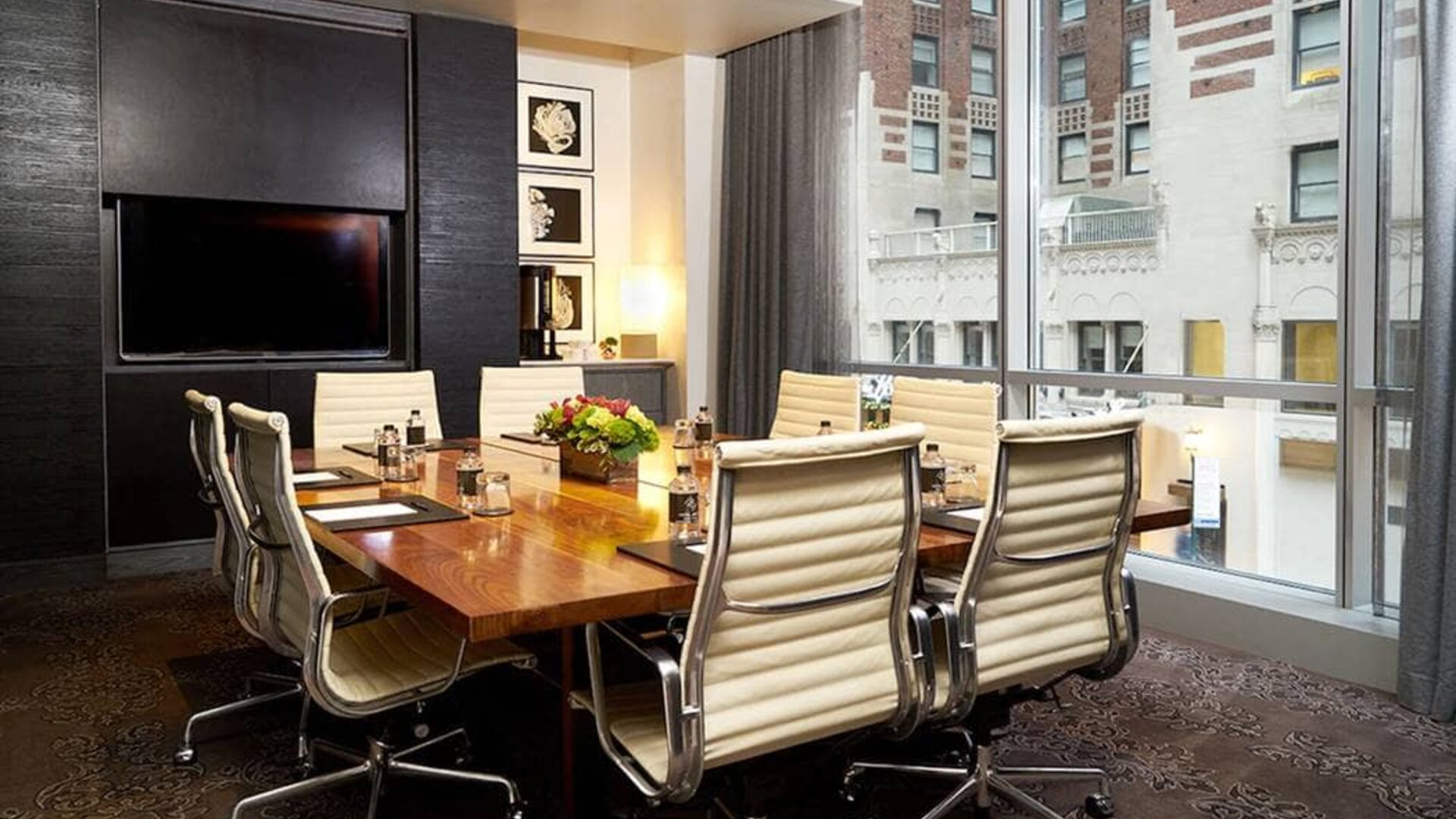 One of the hotel’s meeting rooms, with eight chairs around a long table, and a large TV screen.