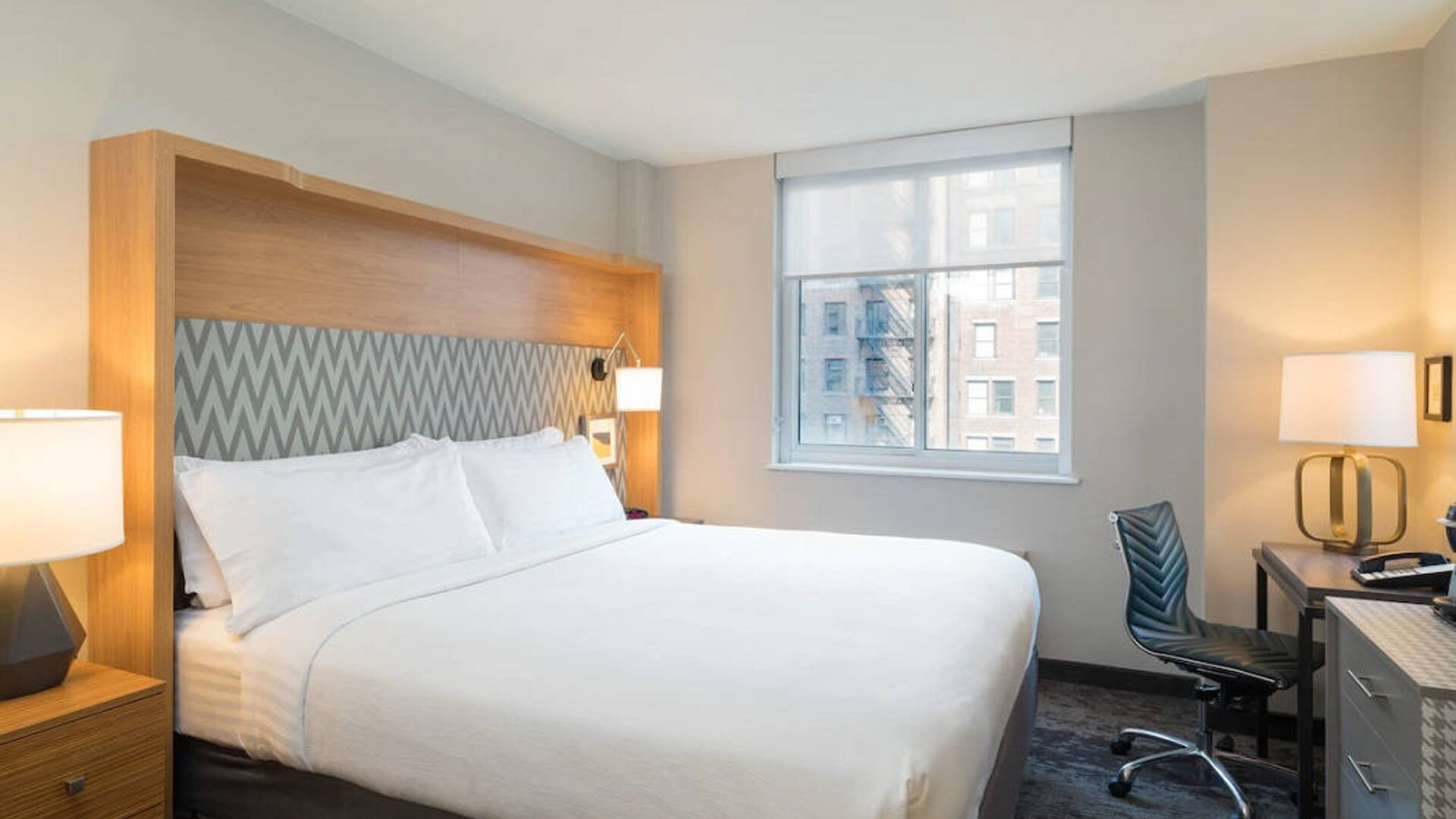 One of Holiday Inn Express Wall Street’s guest rooms, complete with double bed, window, and workspace chair and desk.