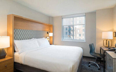 One of Holiday Inn Express Wall Street’s guest rooms, complete with double bed, window, and workspace chair and desk.